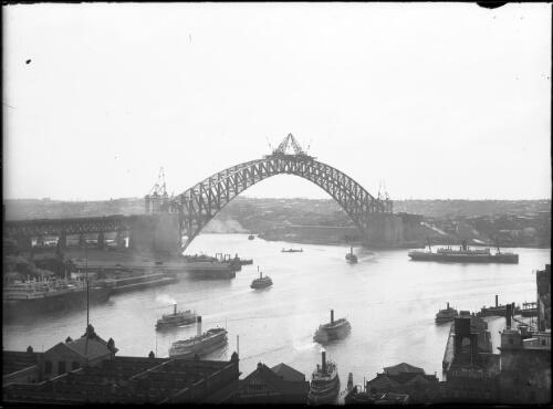 Sydney Harbour Bridge, meeting of the arch; ship at Circular Quay; ferries on harbour, 1930, [3] [picture]