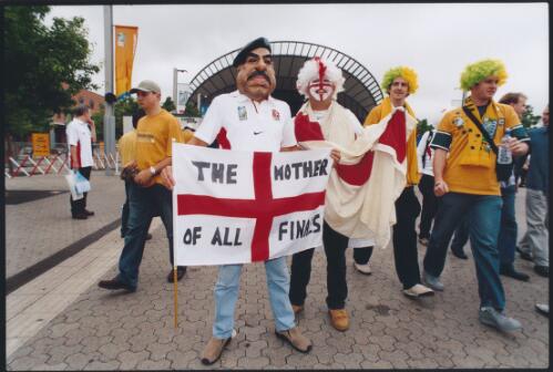 Two English supporters, one of whom wears a Saddam Hussein mask, in front of the Olympic Park Train Station before the Rugby World Cup final, Sydney, November 2003 [picture] / Ben Rushton