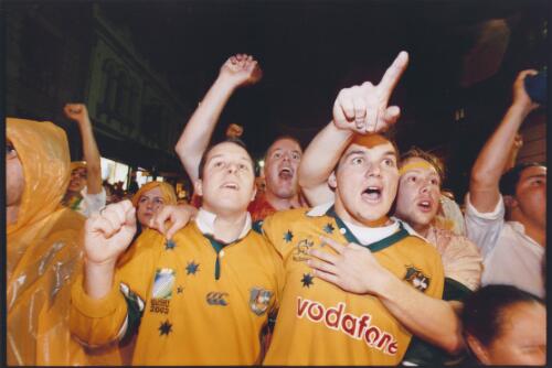 Three friends in the crowd at the Rocks watching the last minutes of the live telecast of the Rugby World Cup final in 2003, Australia lost the final in the last minute, [2] [picture] / Ben Rushton