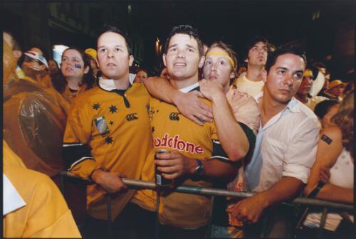 Three friends in the crowd at the Rocks watching the last minutes of the live telecast of the Rugby World Cup final in 2003, Australia lost the final in the last minute, [3] [picture] / Ben Rushton