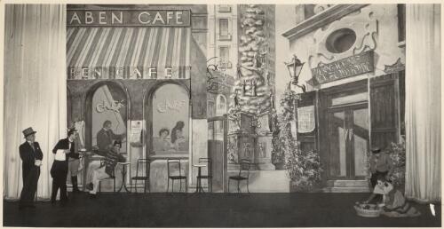 [Scene set in Vienna from an unidentified production, showing a waiter serving a uniformed man outside a café with a man in top hat and gloves looking on and two other performers in front of a nearby restaurant, 19--?] [picture]