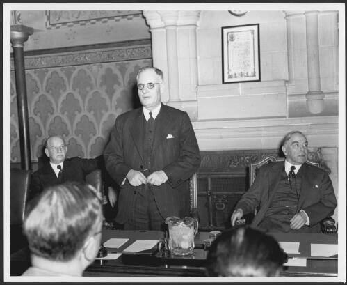 John Curtin addressing a Press conference, Ottawa, 1944, with Canadian Prime Minister Mackenzie King seated right and Hon. J.A Glenn, Speaker, House of Commons seated left [picture]