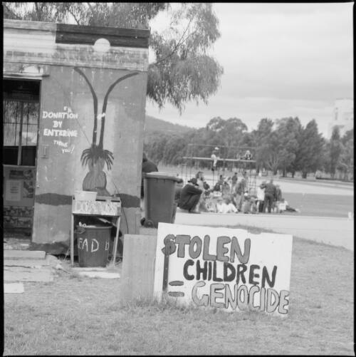 Sign reading Stolen children = genocide placed outside the Aboriginal Tent Embassy opposite Old Parliament House, Canberra, 30 January 1998 [picture] / Loui Seselja