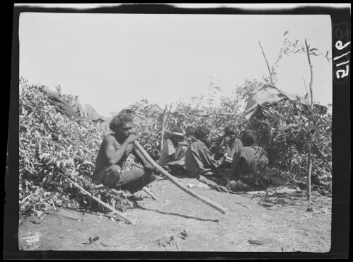 Aboriginal women and children and a man with a didgeridoo in front of their wurley, Wave Hill, Northern Territory, 1925 / Michael Terry