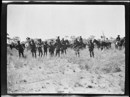 Group of Aboriginal Australian men standing in front of men on horseback, Western Australia, 1925 / Michael Terry