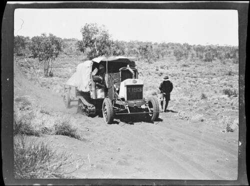 Man standing next to one of the expedition vehicles on a sandy track, Western Australia, 1925 / Michael Terry