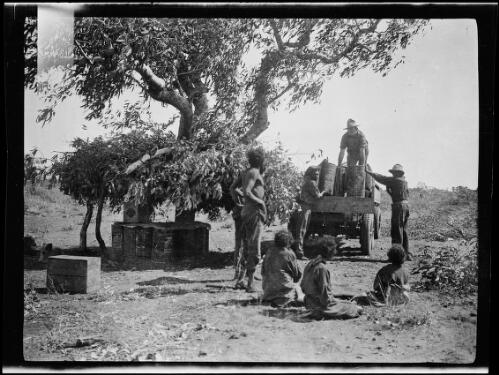Loading petrol to the back of the truck with the help of Aboriginal workers at Tanami Police Camp, Northern Territory, 1928 / Michael Terry