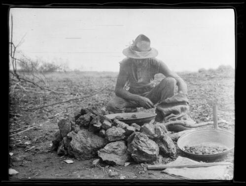 Michael Terry examining rocks in gold pans, Ivy Leases, Tanami Desert, Northern Territory, 1928 / Michael Terry