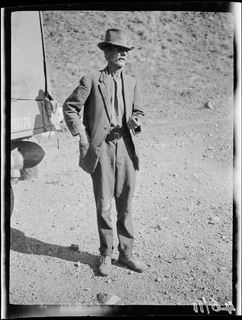 Tom Laurie in a hat and suit standing next to the expedition's truck, Halls Creek Region, Western Australia, 1928 / Michael Terry