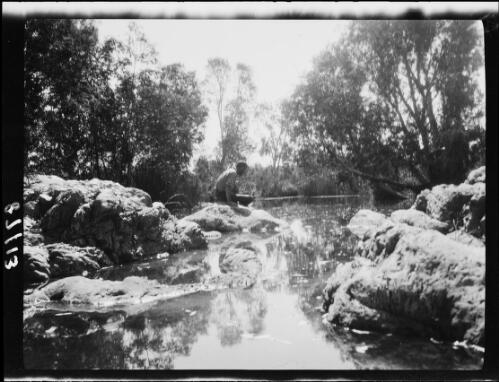 Expedition member sitting on the edge of a waterhole, Northern Territory, 1929 / Michael Terry