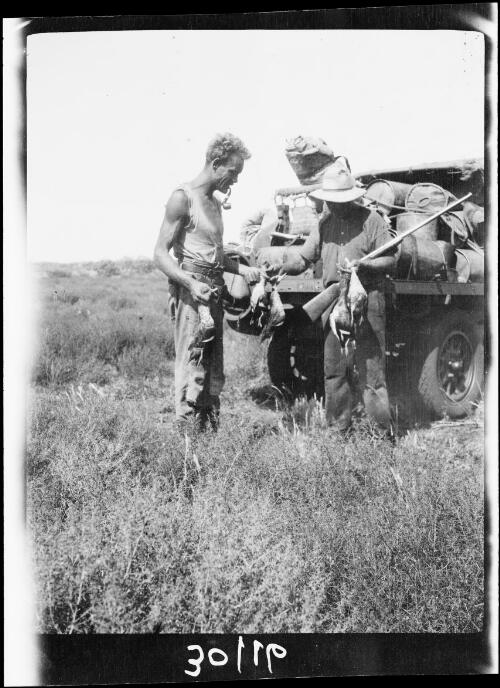 Michael Terry and expedition member Bill Bird with waterfowl standing beside a Morris Commercial truck, Central Australia?, approximately 1930