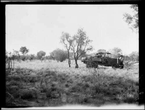 Expedition member standing by a Morris Commercial truck in wooded scrubland, Central Australia?, approximately 1930 / Michael Terry