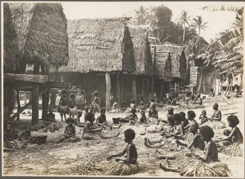Scene in  Mailu Village, [women weaving in front of huts, Papua New Guinea] [picture]