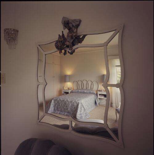 [A mirror reflecting a bed with a carved and lacquered headboard of overlapping oval shapes and a coverlet with a floral pattern, ca. 1971] [transparency] / David Beal