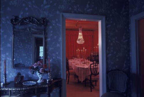 [Looking from a blue hallway with side table and mirror into a pink dining room with oval chandelier, ca. 1971] [transparency] / David Beal