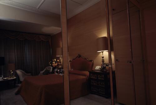 [Wood panelled bedroom with a pink bed and wooden bedside tables, reflected in large mirrors, ca. 1971] [transparency] / David Beal