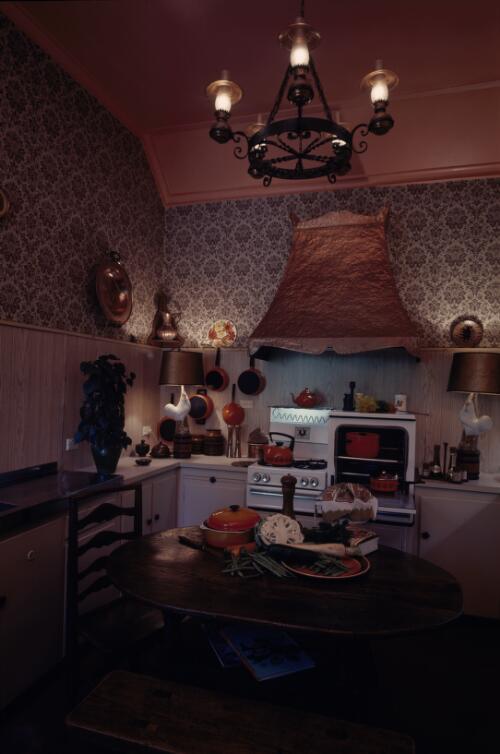 [Kitchen with brown and black damask wallpaper,  a copper hood, wooden panelling, oiled furniture and black iron hanging lights, ca. 1971] [transparency] / David Beal