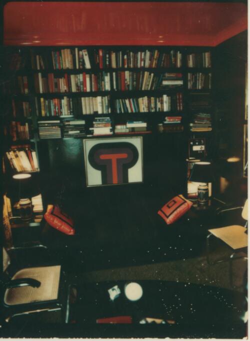Library with a wall of books and shiny red ceiling above a black sofa with square cushions, ca. 1971 [picture] / David Beal