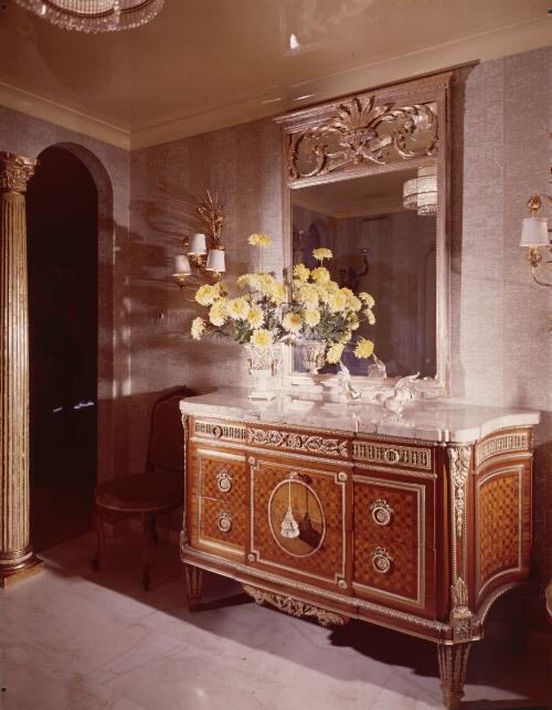 [Gold and silver leaf columns rise from the marble floors of an annexe and support the arched openings to the drawing-room beyond, an Empire marquetry commode (circa 1800) in kingwood and emboyna with finely chiselled ormolu mounts is oaklined while the wall-brackets and mirror frame are also gold, ca. 1971] [transparency] / David Beal