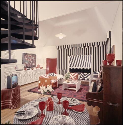 [A black iron spiral staircase winds from a mezzanine gallery to this family room, ca. 1971] [transparency] / David Beal