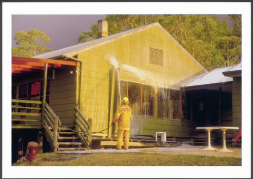 With a major fire approaching from Corin Dam, bushfire fighters at Corin Forest resort at Smokers Gap saturated buildings and facilities, [17 January 2003] [picture] / Jeff Cutting