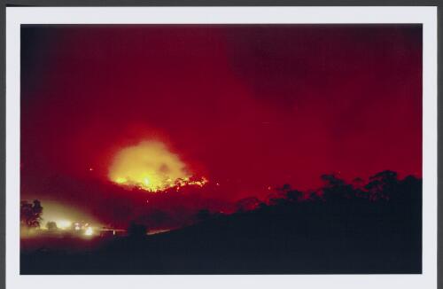 Bushfire tankers on property protection duty mill around a homestead facing the Monaro Highway as fire burns over Clearview Range at dusk on 30th January 2003 [picture] / Jeff Cutting