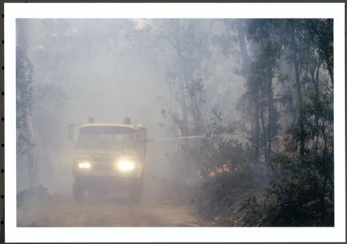A heavy tanker using the hard-hitting water cannon to knock down a spot-over alongside Moonlight Hollow Road on Bendora Hill, [11 January 2003] [picture] / Jeff Cutting
