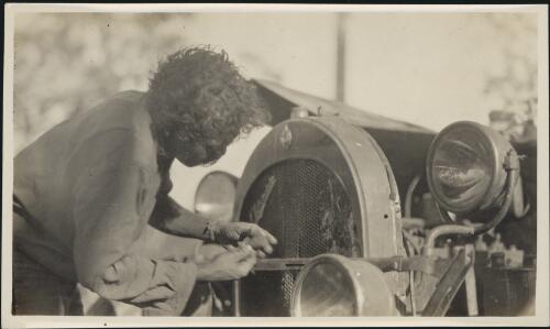 [An Aboriginal mechanic using the sap of the bloodwood tree and a hot stick to repair the Oldsmobile 30, Arnhem Land] [picture]