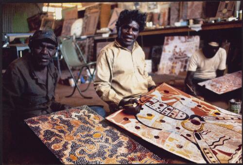 [Artists Charlie Tarawa (Tjaruru) Tjungurrayi, Johnny Warangkula Tjupurrula and Timmy Payungka Tjapangati with their paintings, Papunya, 1972] [picture] / Michael Jensen