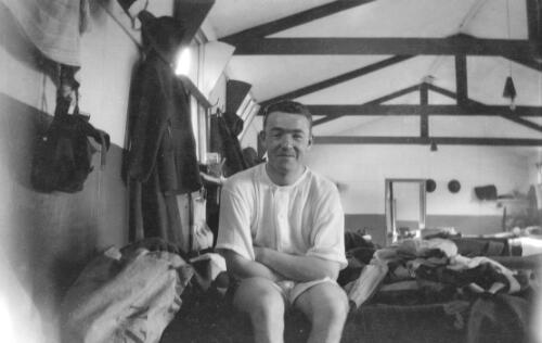 New Zealand WW1 soldier seated on bed in camp [picture] / Rex Nan Kivell
