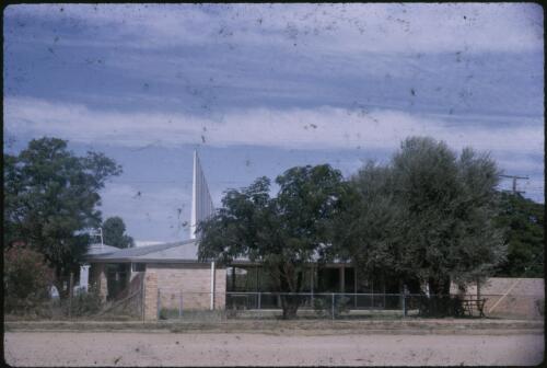 Light brown brick church with a spire, ca. 1964 [transparency] / Les McKay