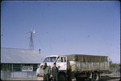 Two men beside a Bedford truck full of explosives, A.I.M. Nursing Home, Birdsville, Queensland, 1964 [transparency] / Les McKay