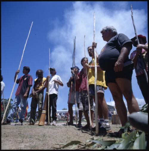 [Aboriginal people standing with wooden sticks at ceremony for 30th Anniversary of the Aboriginal Tent Embassy, Canberra, 26 January 2002] [transparency] / Loui Seselja