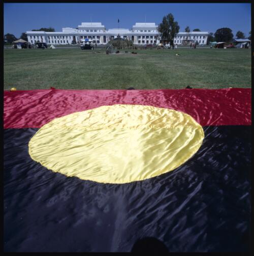 [The Aboriginal flag with Old Parliament House in background, on 30th anniversary of Aboriginal Tent Embassy, Canberra, 26 January 2002] [transparency] / Loui Seselja