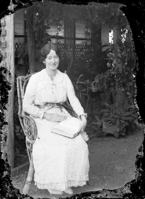 Gertie Lamont seated with book in fernery, Clermont, Queensland, ca. 1920 [picture] / Gordon Cumming Pullar