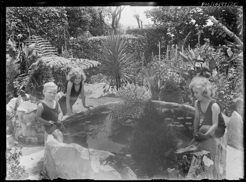 Frank Hurley Junior, on left, with his sisters Toni, centre, and Adelie, right, playing in the fishpond at Stonehenge, Rose Bay, Sydney, ca. 1928 [picture] / Frank Hurley