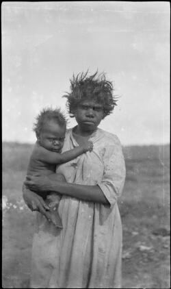 Portrait of an Aboriginal woman holding a small child on an outback ...