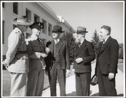 Two armed force personnel, James Scullin fourth from left, and two men outside Parliament House, Canberra, ca. 1945 [picture] / Department of Information