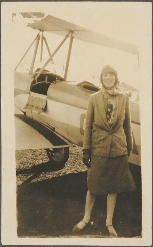 Ann Bernard standing in front of Alexander Eaglerock A2 biplane G-AUGK on a field, Sydney, ca. 1928, 1 [picture]