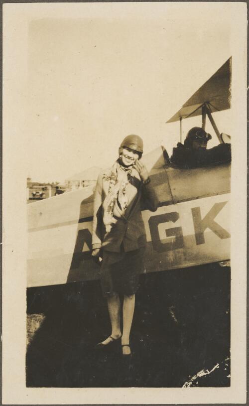 Ann Bernard standing in front of Alexander Eaglerock A2 biplane G-AUGK on a field, Sydney, ca. 1928, 2 [picture]