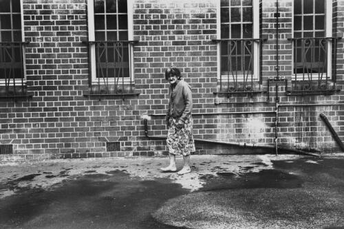A woman standing barefoot outside Northfield Mental Hospital, South Australia, ca. 1965 [picture] / Roy McDonald