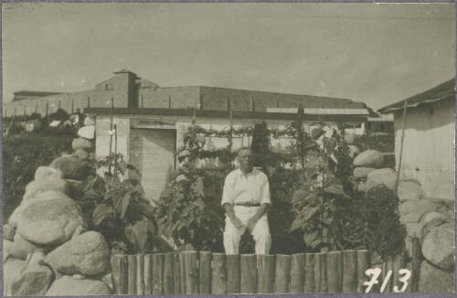 Man sitting in a small vegetable garden with the barracks in the background, Trial Bay, New South Wales, ca.1917 [picture]