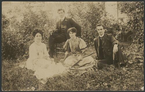 Two women and two men sitting in the garden, with one woman holding a tennis racquet, Walhalla, Victoria, ca. 1890 [picture]