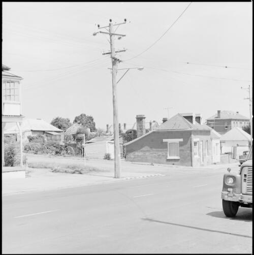 Intersection lined with sandstone houses and an electricity pole on the corner at Oatlands, Tasmania, ca. 1970 [picture] / Wes Stacey
