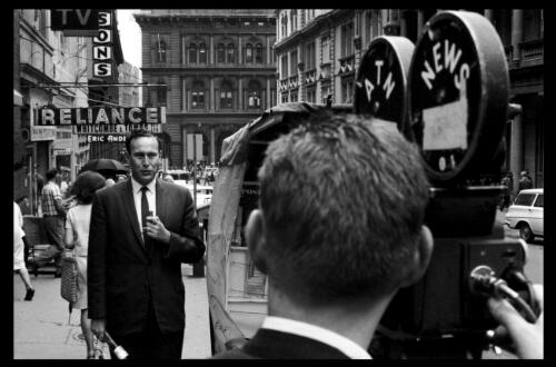 Television news reporter and cameraman filming on a street, 1963 [picture] / Robert McFarlane
