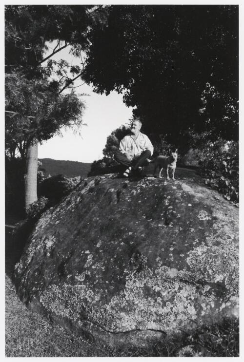 Jeff Carter sitting on a boulder with a dog, Foxground, New South Wales, 1999 / Robert McFarlane
