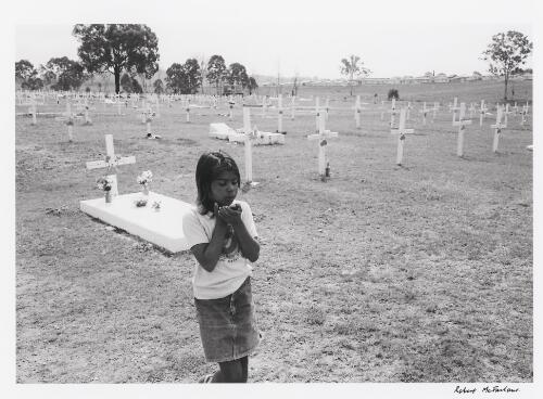 Young Aboriginal Australian girl Melissa Fisher visiting her grandmother's grave, Cherbourg, Queensland, 1986 / Robert McFarlane