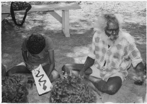 Teenage boy painting on bark under the instruction of an Aboriginal elder, Mornington Island, Queensland, approximately 1980 / Gregory Owen