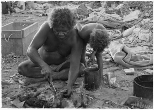 Lardil man cutting meat from a cooked wallaby, Mornington Island, Queensland, approximately 1980 / Gregory Owen