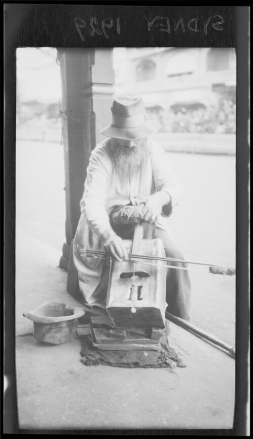 Man busking with a one-string fiddle made from a kerosene tin, Sydney, 1929